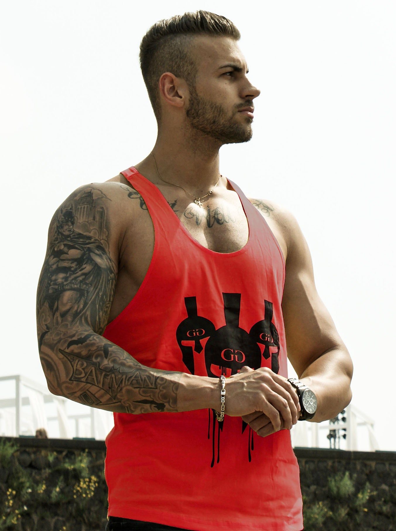 Athlet trägt das rote Gym Generation Stringer Tank Top mit schwarzem Spartaner-Helm-Design, perfekt für Fitness und Lifestyle.