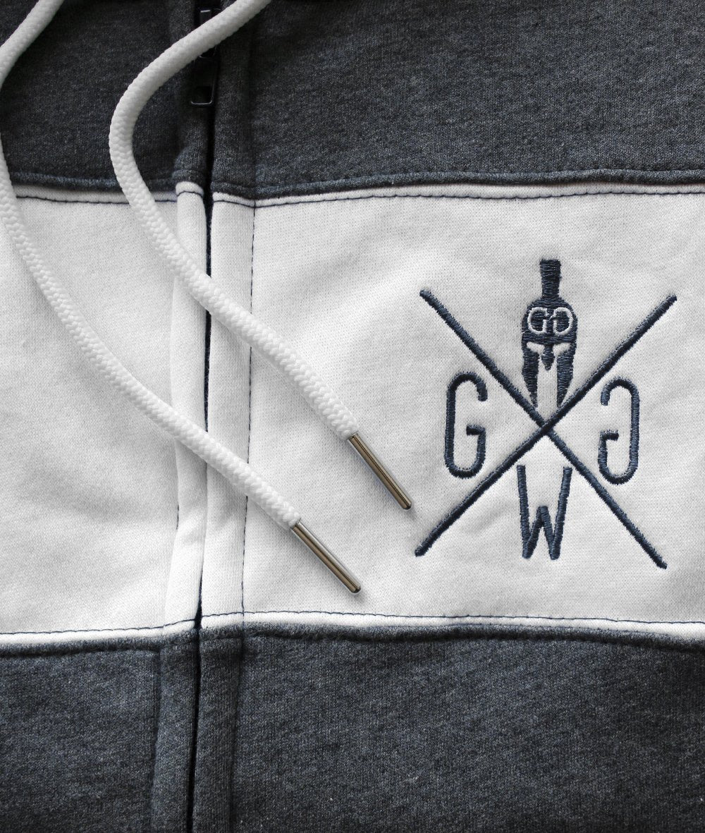 Detailansicht des gestickten Gym Warriors Logos auf einem ärmellosen Hoodie in Dunkelgrau mit weißem Streifen und Kordelzug.