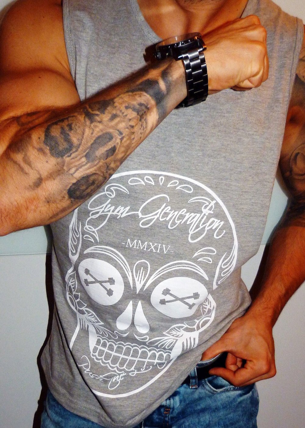 Mann mit Totenkopf Tattoo am Unterarm trägt Gym Tank Top mit Totenkopf Print von Gym Generation im Streetstyle Look.