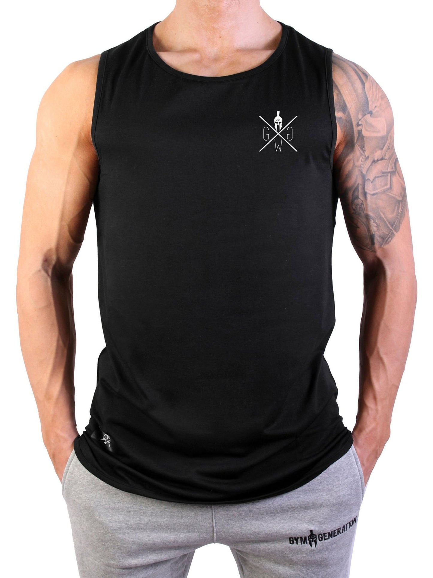 Vorderansicht eines Mannes im Gym Generation Muscle Tank Top in Schwarz, kombiniert mit grauen Fitness-Jogginghosen, zeigt minimalistisches Design und athletische Passform.